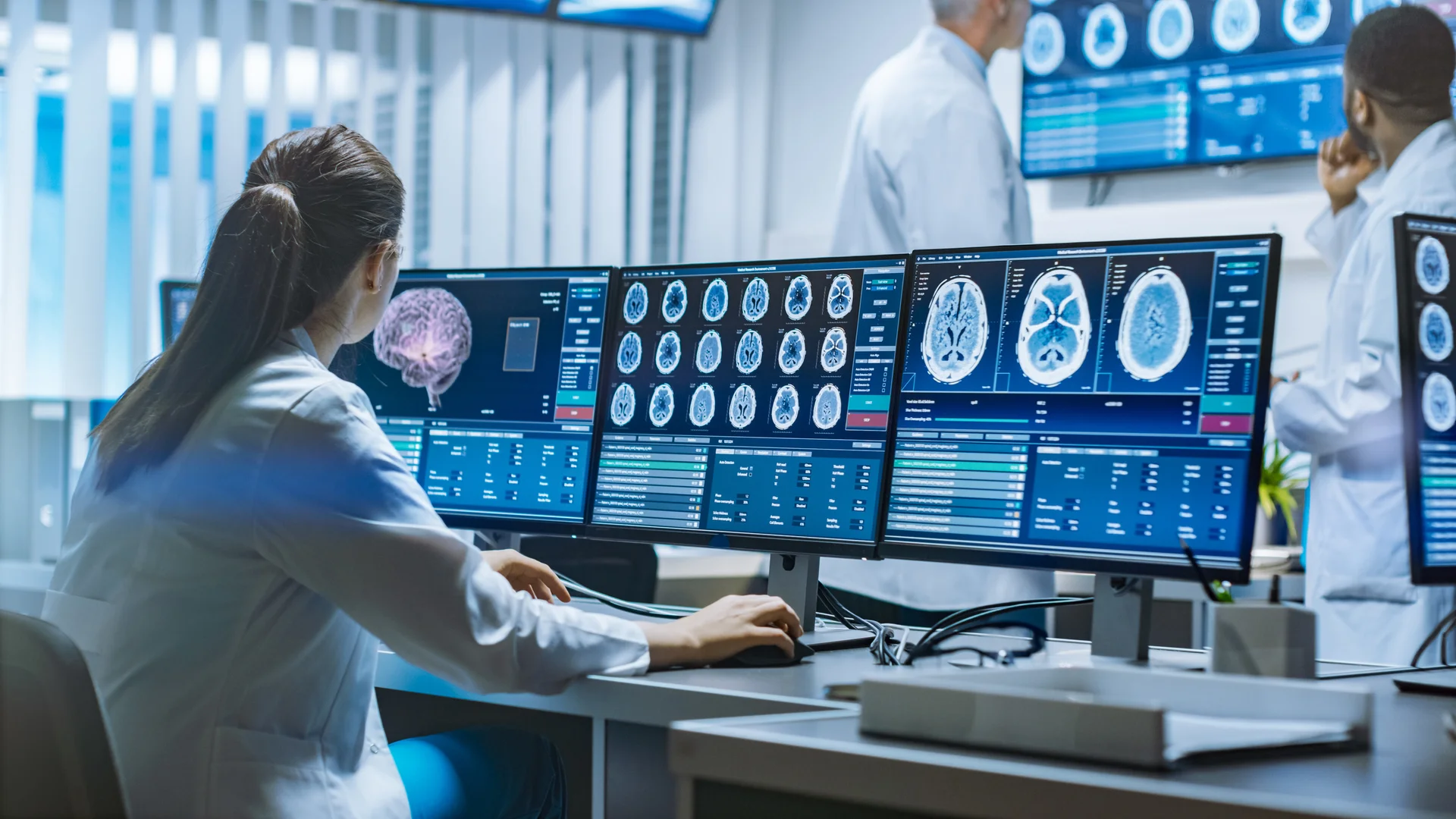Medical professional working with multiple monitors displaying medical imaging data